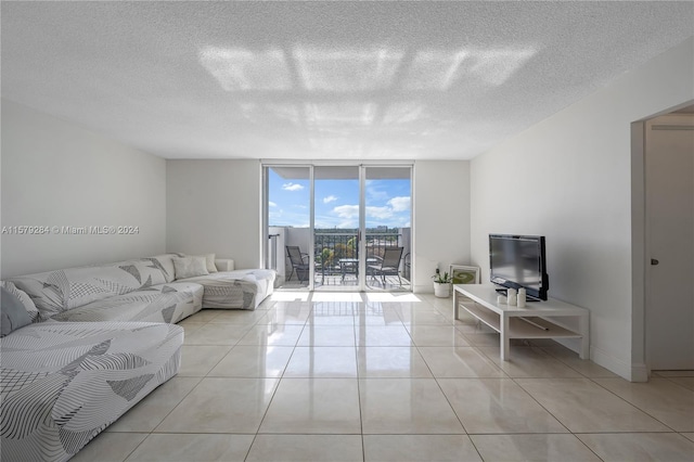 living room with a textured ceiling, a wall of windows, and light tile flooring