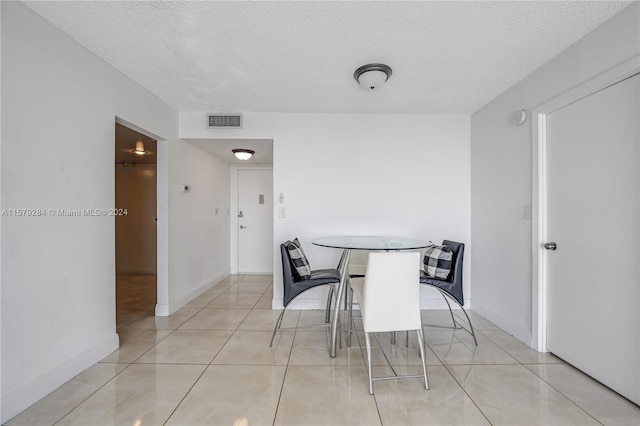 unfurnished dining area featuring a textured ceiling and light tile flooring