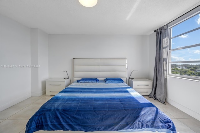 bedroom with a textured ceiling and light tile flooring