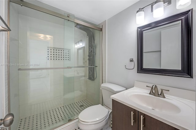 bathroom featuring a shower with door, vanity, and toilet