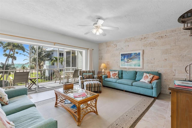 living room featuring tile walls, a textured ceiling, ceiling fan, and light tile floors