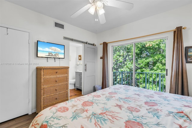 bedroom with ceiling fan, a barn door, ensuite bath, access to exterior, and hardwood / wood-style flooring