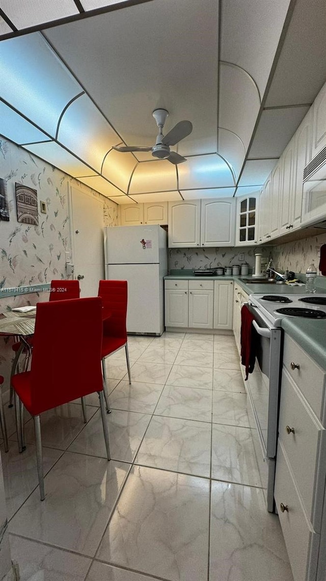 kitchen with ceiling fan, white appliances, backsplash, light tile floors, and white cabinets