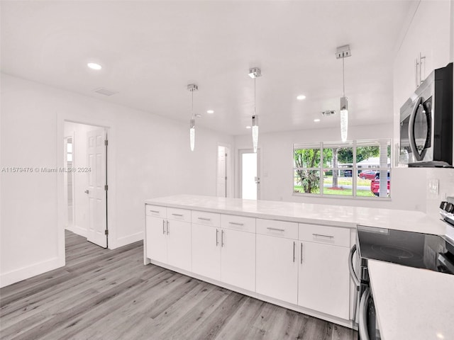 kitchen with white cabinets, hanging light fixtures, light wood-type flooring, and range with electric stovetop