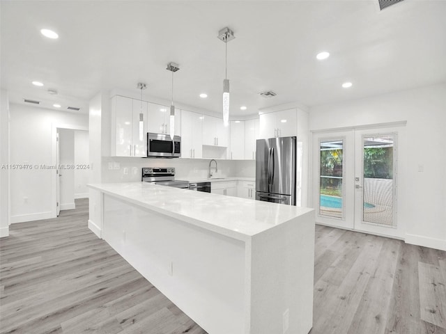 kitchen with white cabinets, sink, light hardwood / wood-style floors, stainless steel appliances, and pendant lighting