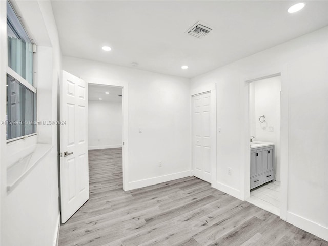 interior space featuring a closet, light hardwood / wood-style flooring, and connected bathroom