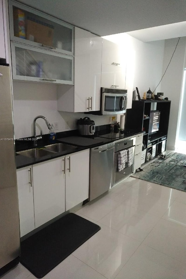 kitchen with white cabinets, sink, light tile floors, and stainless steel appliances