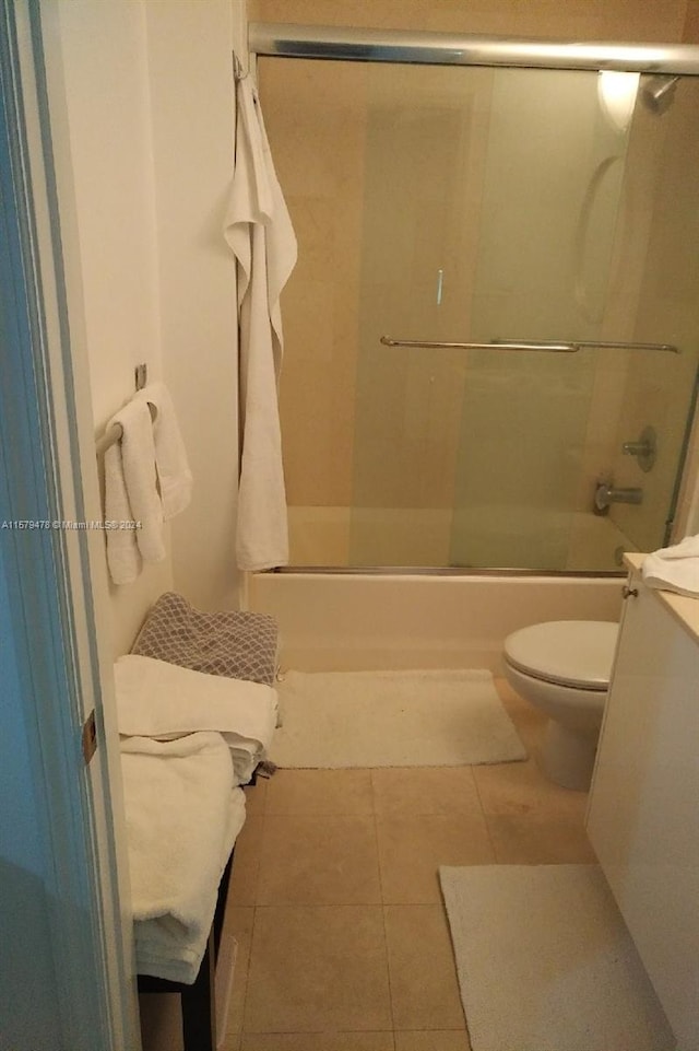 bathroom with enclosed tub / shower combo, toilet, and tile floors