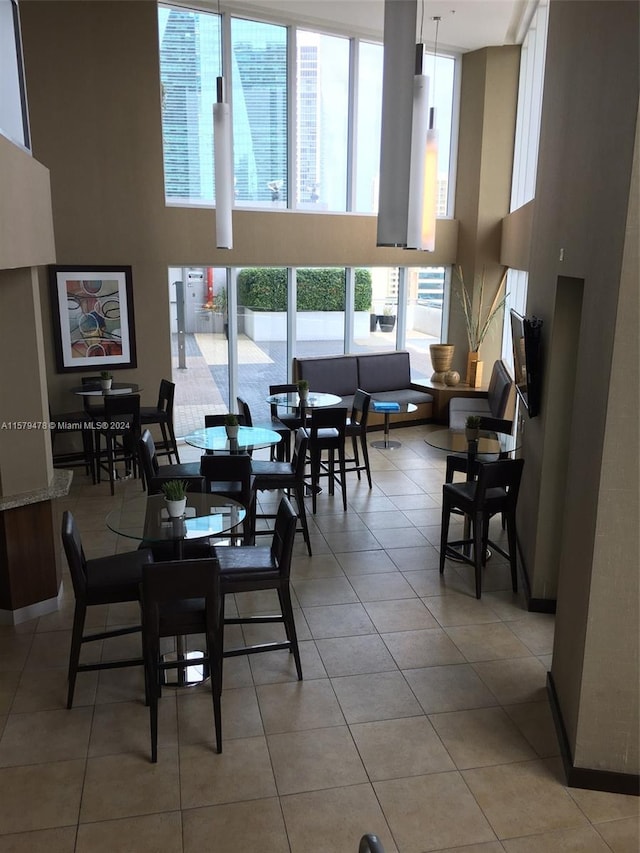 dining room with a towering ceiling and light tile floors