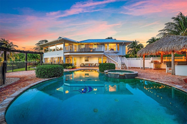 pool at dusk with an in ground hot tub and a patio