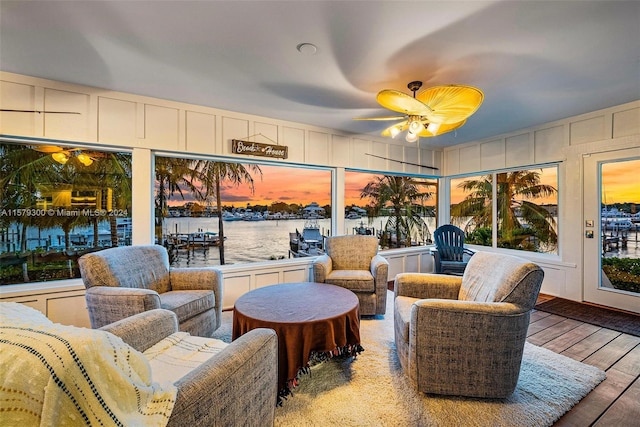 sunroom / solarium with a water view and ceiling fan