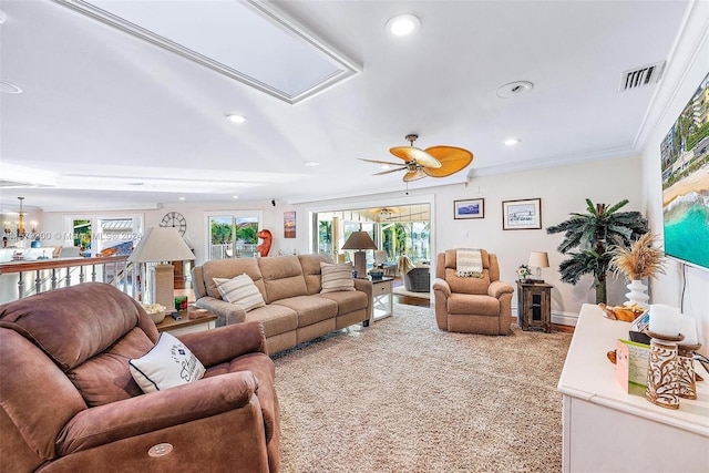 carpeted living room with a healthy amount of sunlight, crown molding, and ceiling fan with notable chandelier