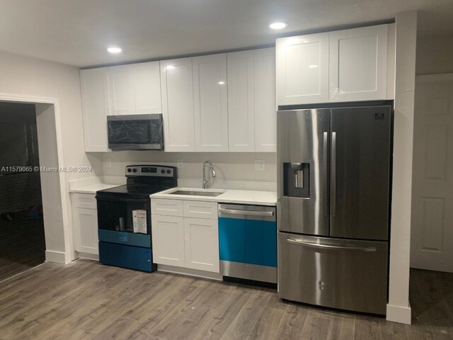 kitchen with appliances with stainless steel finishes, light hardwood / wood-style flooring, sink, and white cabinetry