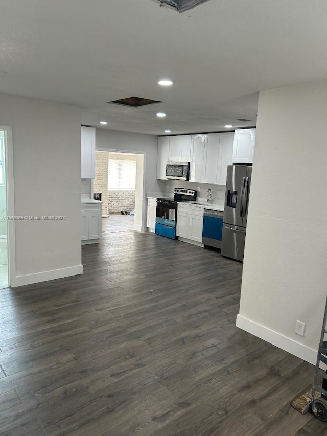 kitchen with dark wood-type flooring, stainless steel appliances, and white cabinetry