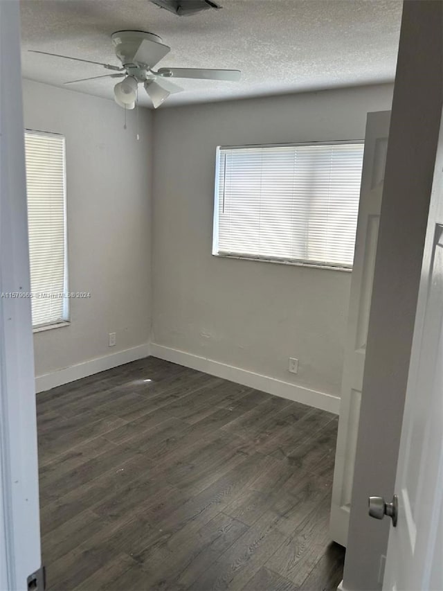 unfurnished room with dark wood-style floors, ceiling fan, a textured ceiling, and baseboards