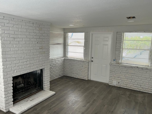 entryway with dark wood-style floors, brick wall, a brick fireplace, and a textured ceiling