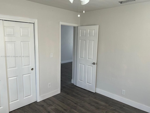 unfurnished bedroom featuring dark wood-style floors, visible vents, and baseboards