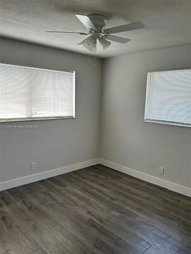 spare room featuring a textured ceiling, ceiling fan, dark wood finished floors, and baseboards