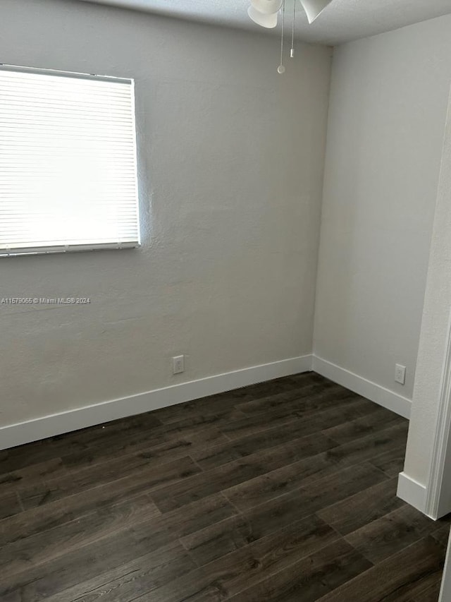 empty room featuring baseboards and dark wood finished floors