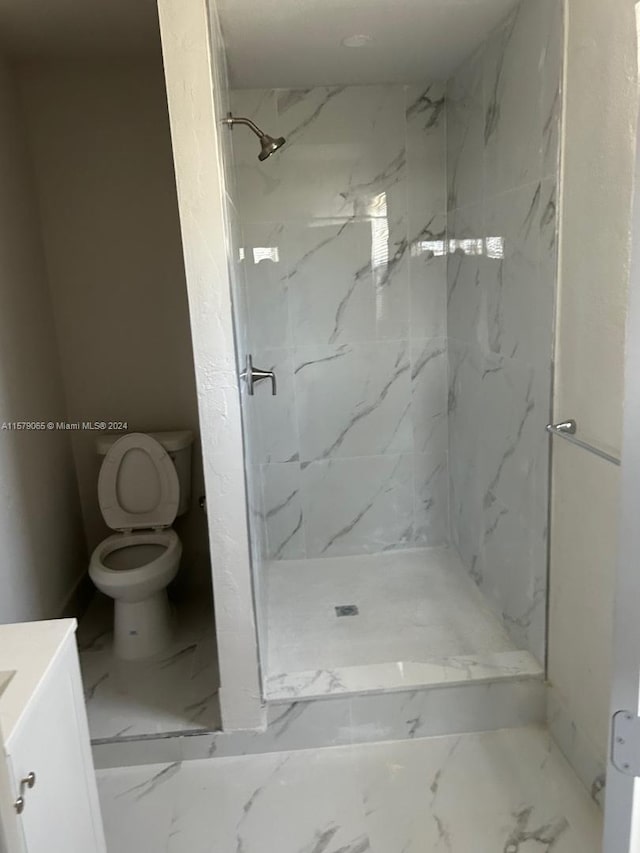 bathroom with a marble finish shower, marble finish floor, toilet, and vanity