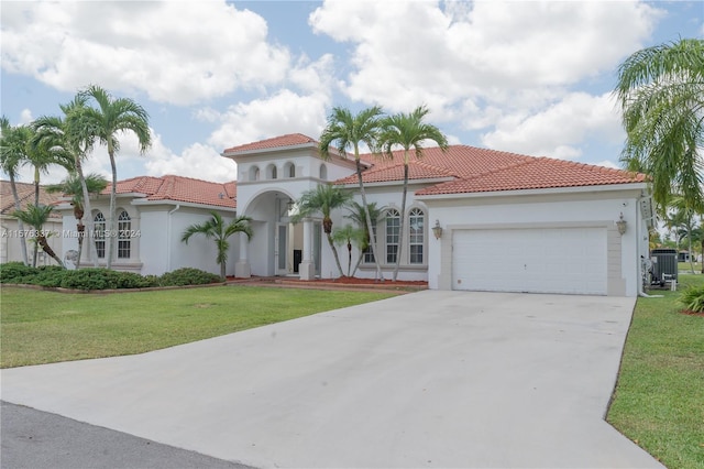 mediterranean / spanish home featuring a garage, concrete driveway, a front yard, and stucco siding