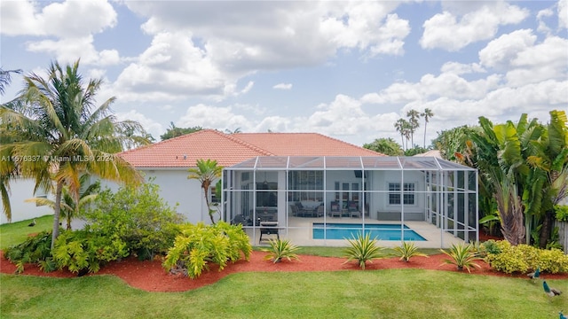 rear view of property with a lanai, an outdoor pool, a tile roof, a yard, and stucco siding