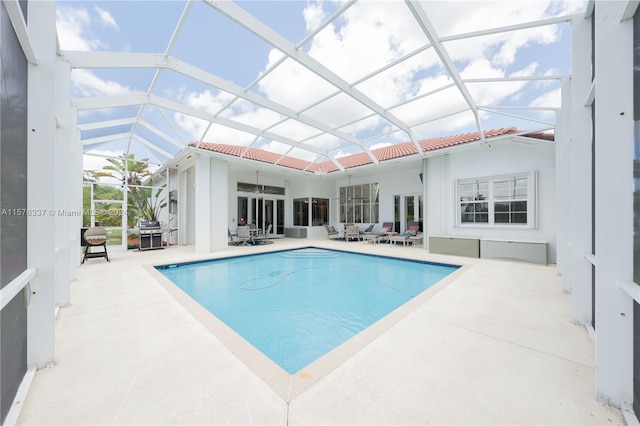 view of pool with a lanai, ceiling fan, grilling area, and a patio