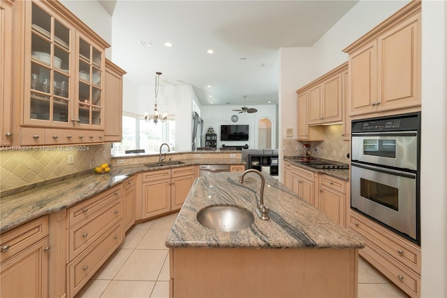 kitchen featuring appliances with stainless steel finishes, open floor plan, a center island with sink, and a sink