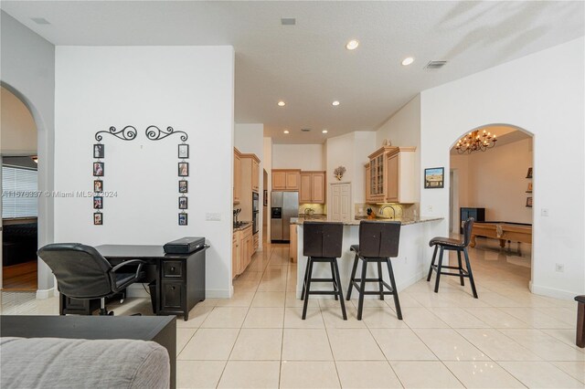 kitchen with stainless steel fridge, light tile patterned floors, a kitchen breakfast bar, and kitchen peninsula