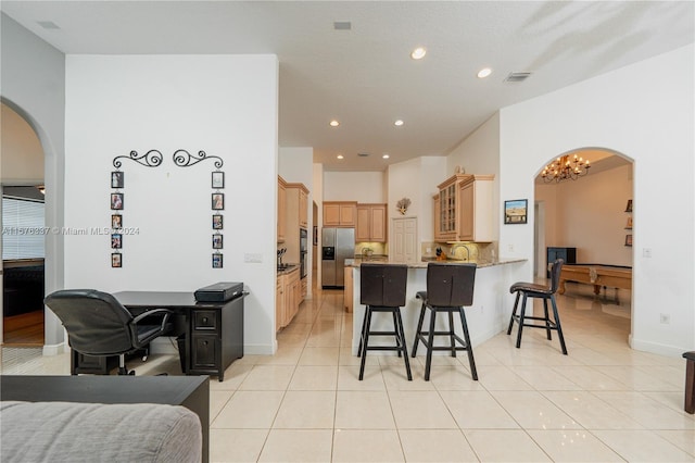 kitchen with arched walkways, a peninsula, visible vents, appliances with stainless steel finishes, and a kitchen bar