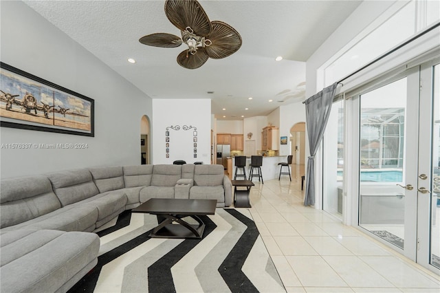 living room with a textured ceiling, ceiling fan, and light tile patterned flooring