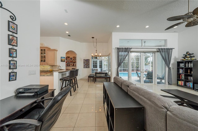 living area with light tile patterned floors, recessed lighting, arched walkways, a textured ceiling, and ceiling fan with notable chandelier