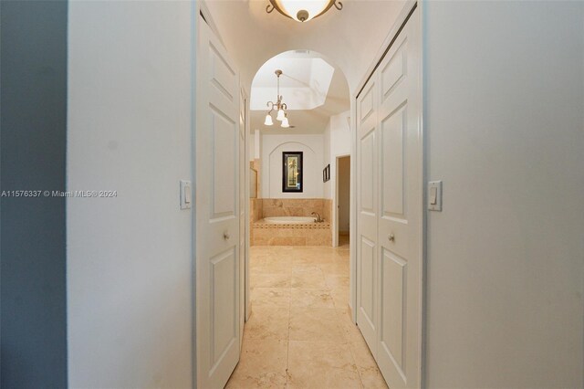 hall with a chandelier and light tile patterned floors