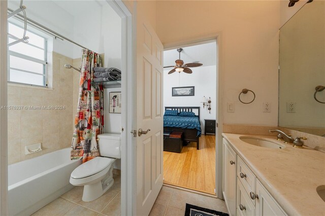 full bathroom featuring tile patterned flooring, shower / bathtub combination with curtain, toilet, ceiling fan, and vanity