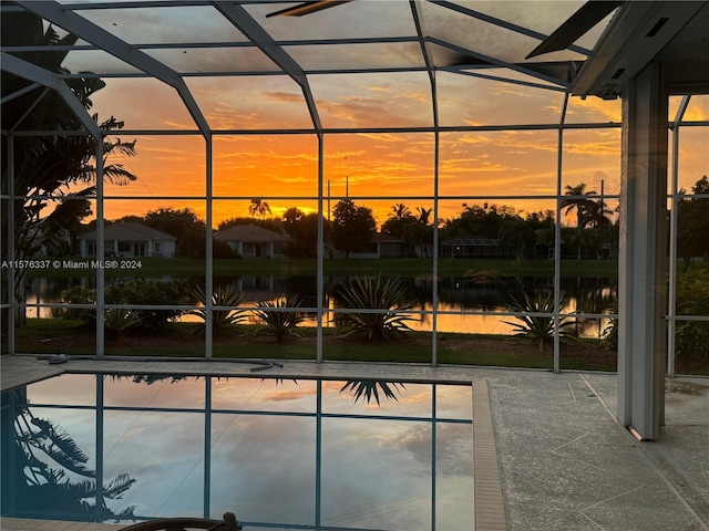 view of pool with a water view, a patio area, and glass enclosure