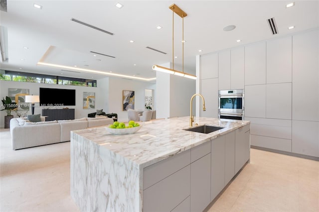 kitchen with pendant lighting, sink, white cabinetry, a spacious island, and stainless steel double oven