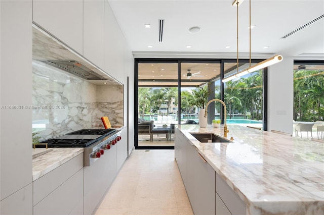 kitchen with pendant lighting, white cabinetry, sink, stainless steel gas cooktop, and light stone counters