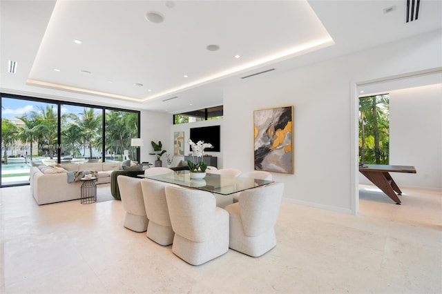 dining room featuring floor to ceiling windows and a raised ceiling