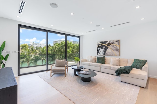 living room with a wall of windows and light hardwood / wood-style floors