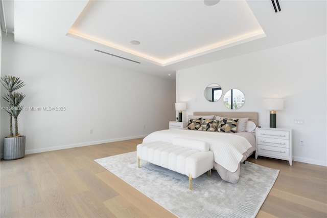 bedroom featuring a raised ceiling and light hardwood / wood-style flooring