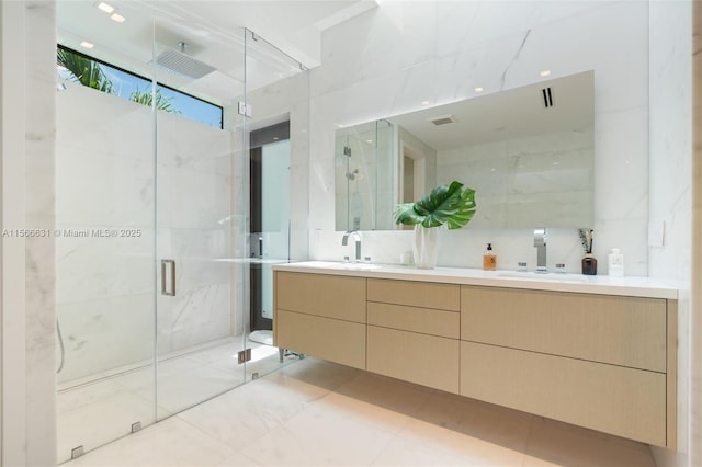 bathroom with tile walls, vanity, and a shower with door