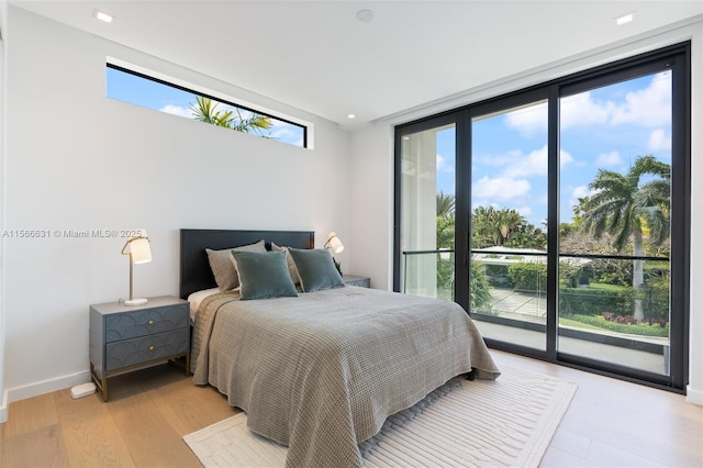 bedroom with access to exterior, a wall of windows, and light hardwood / wood-style floors