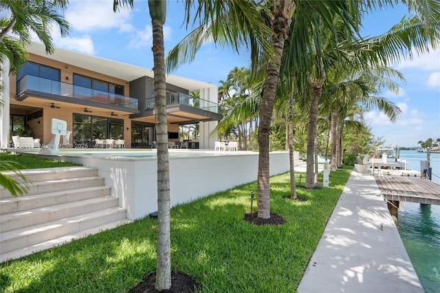 view of home's exterior with a water view, a balcony, a dock, and a patio