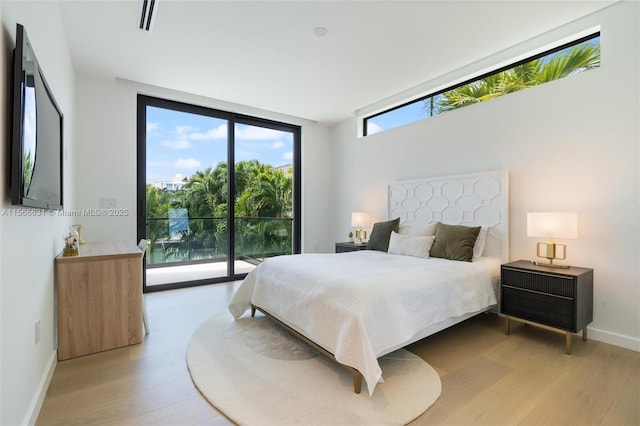 bedroom featuring floor to ceiling windows, access to exterior, and light hardwood / wood-style flooring