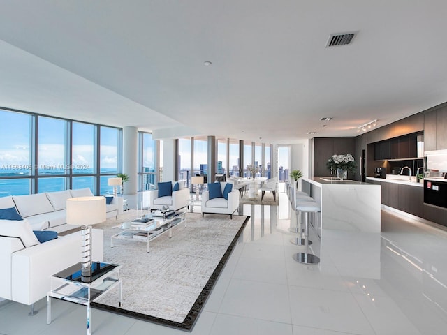 tiled living room with expansive windows, sink, and a water view