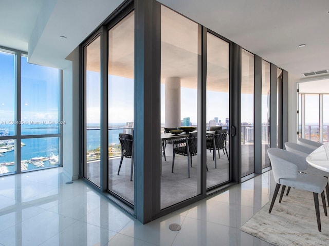 interior space with floor to ceiling windows, light tile floors, and a water view