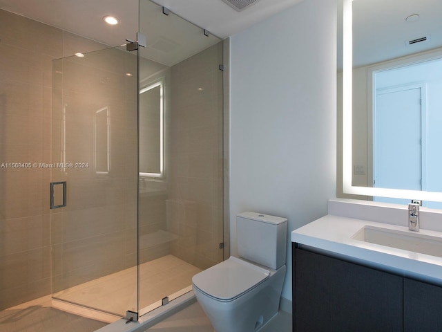 bathroom with a shower with shower door, toilet, and vanity