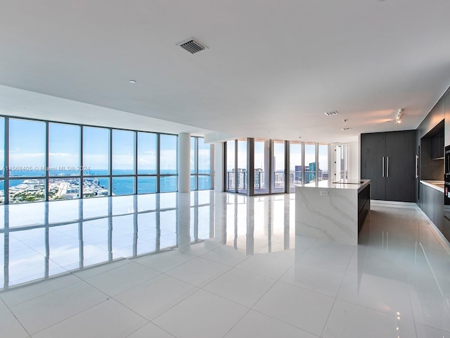 tiled empty room with sink, a wall of windows, and a water view