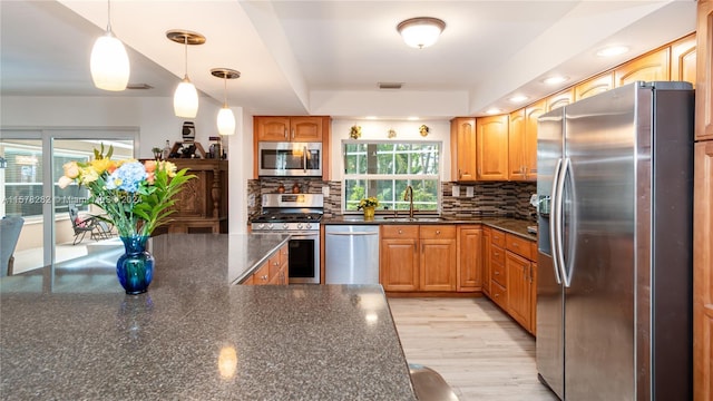 kitchen with pendant lighting, sink, backsplash, stainless steel appliances, and a raised ceiling