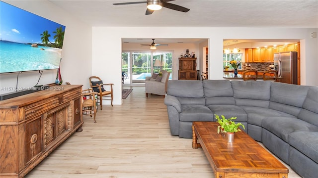 living room with ceiling fan with notable chandelier, a textured ceiling, and light hardwood / wood-style floors